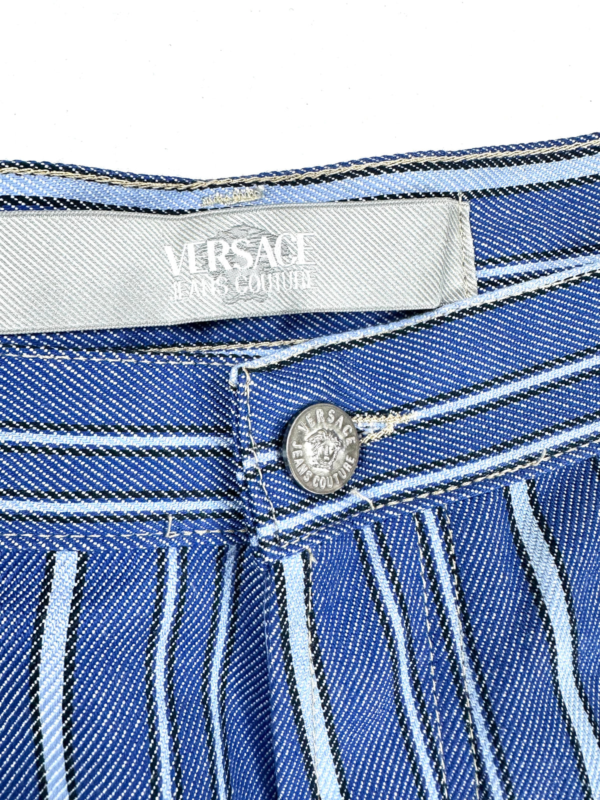 Etichetta Versace Jeans Couture sul retro della cintura, accanto al bottone con Medusa