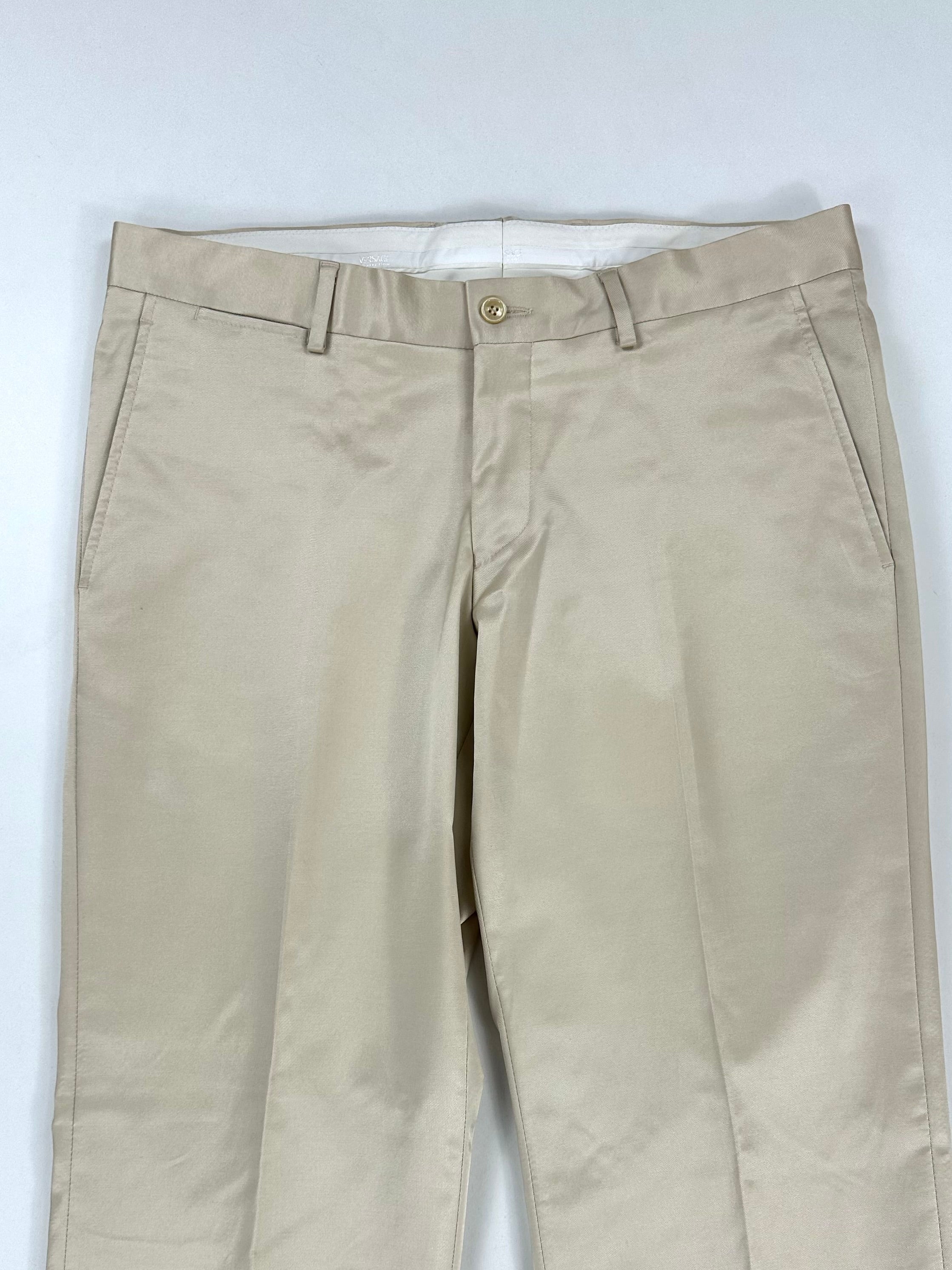 Parte alta del pantalone panna: passanti in vita, chiusura a bottone e tasche laterali oblique
