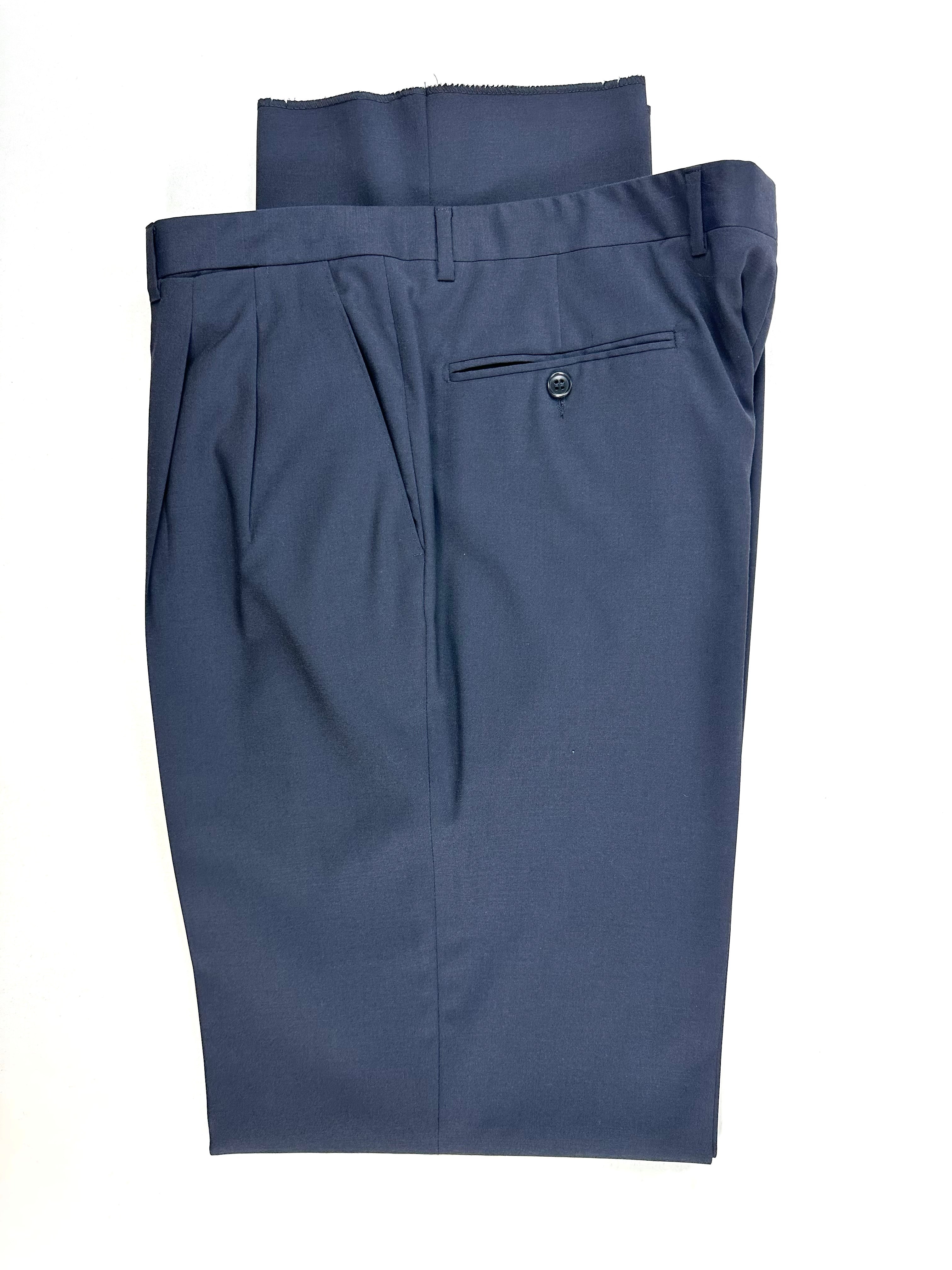 Dettaglio del pantalone piegato: vita, passanti e tasca posteriore a filetto con bottone