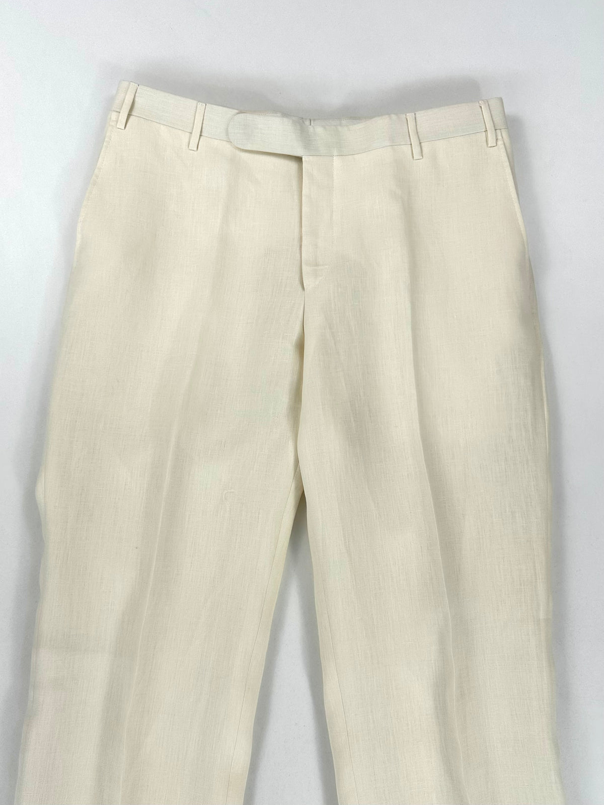 Vita e cintura del pantalone in lino viste dall'alto, con passanti e chiusura frontale