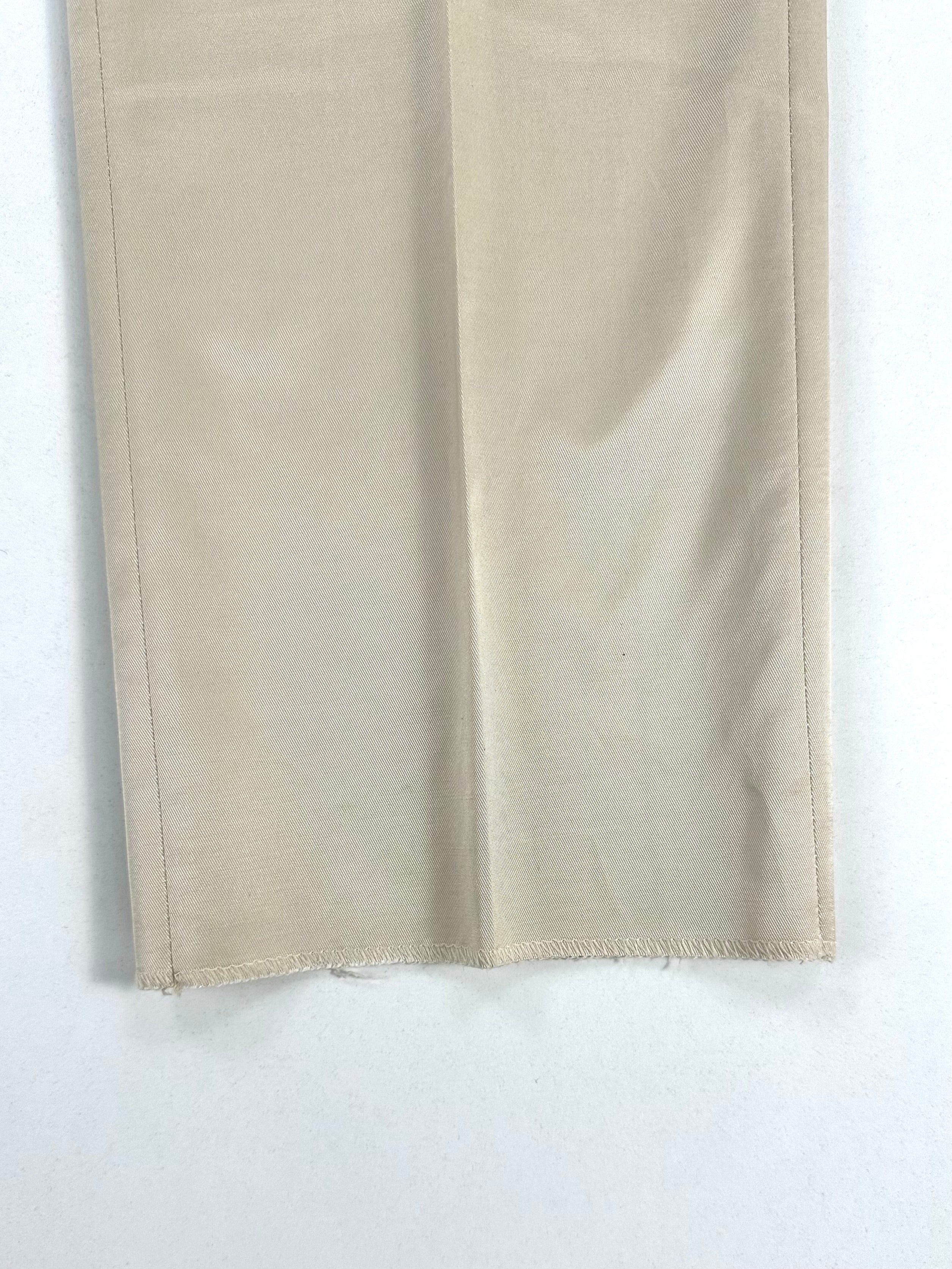 Dettaglio della gamba del pantalone: trama diagonale del tessuto satinato e fondo non orlato