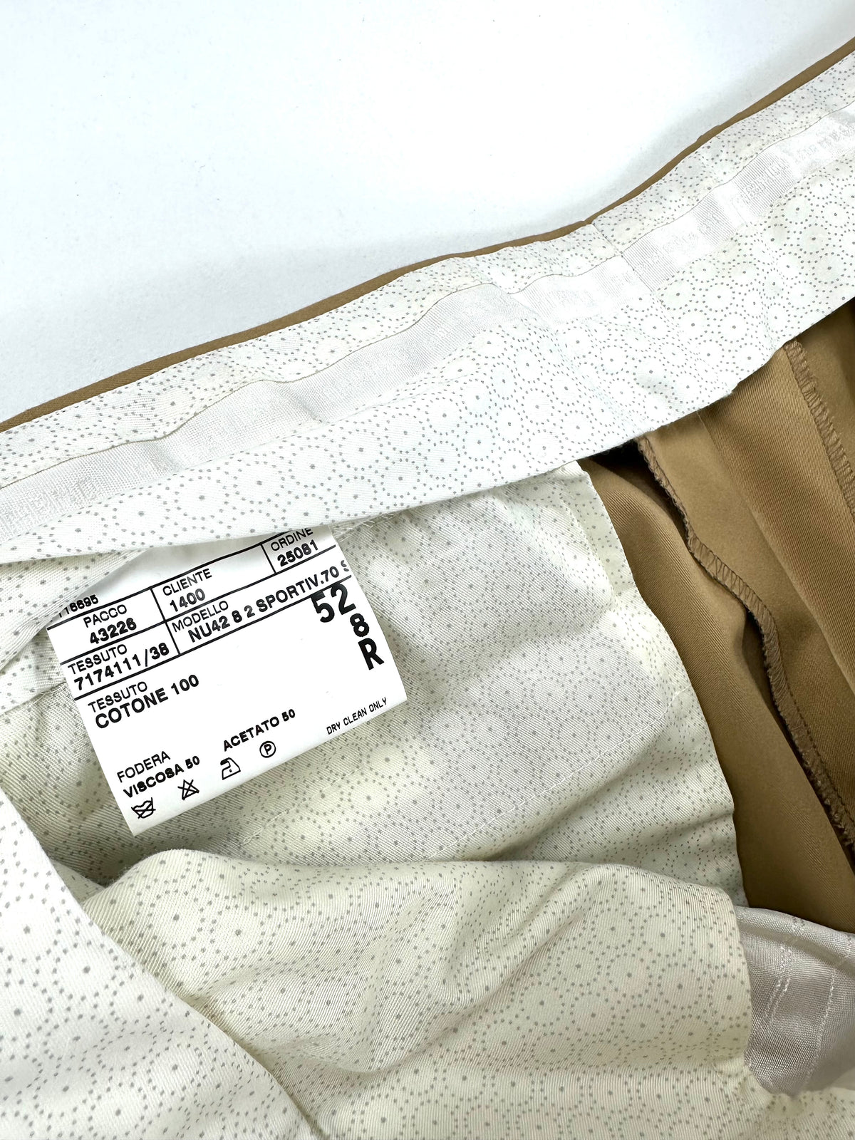 Etichetta interna del pantalone con composizione cotone 100 e taglia, sulla fodera della cintura