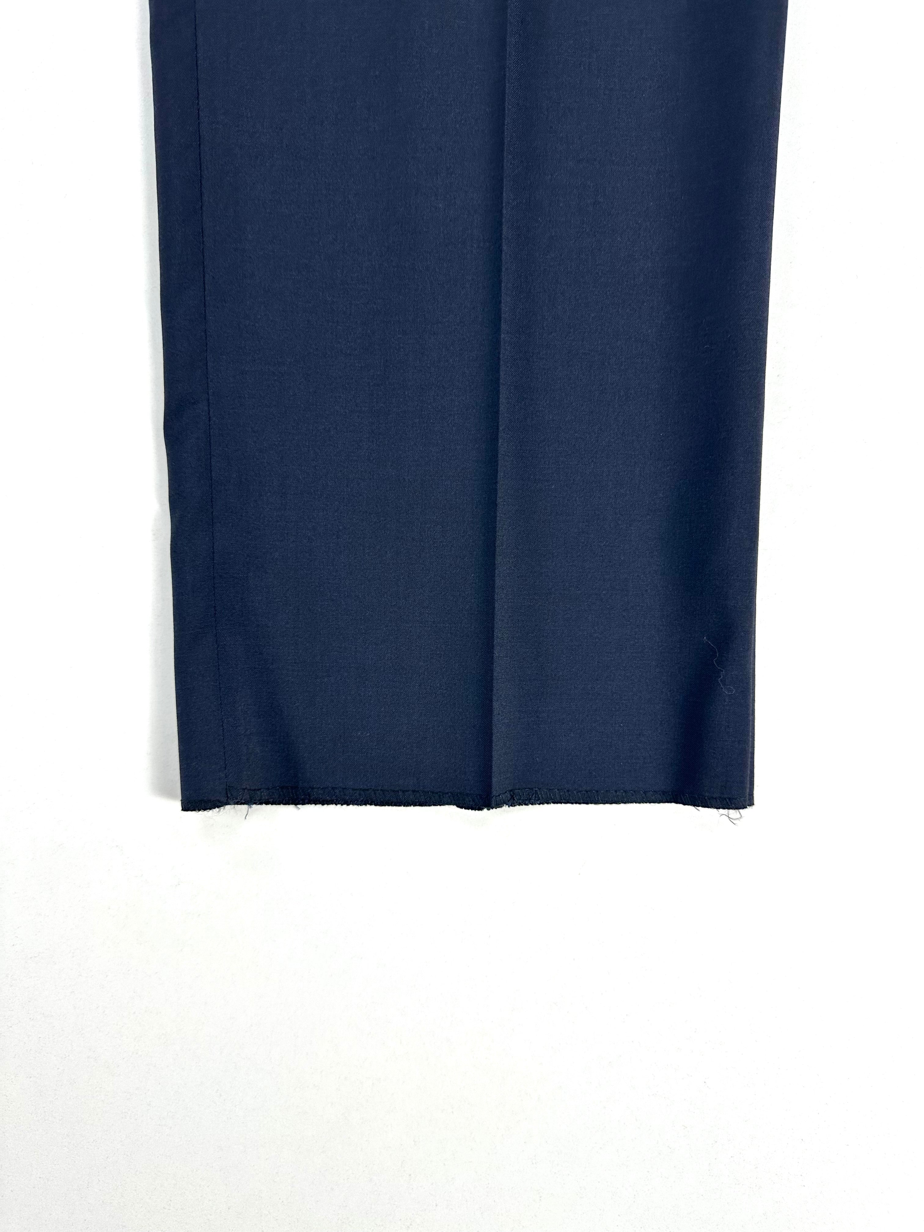 Dettaglio di una gamba del pantalone blu ripiegata, con il fondo grezzo non orlato