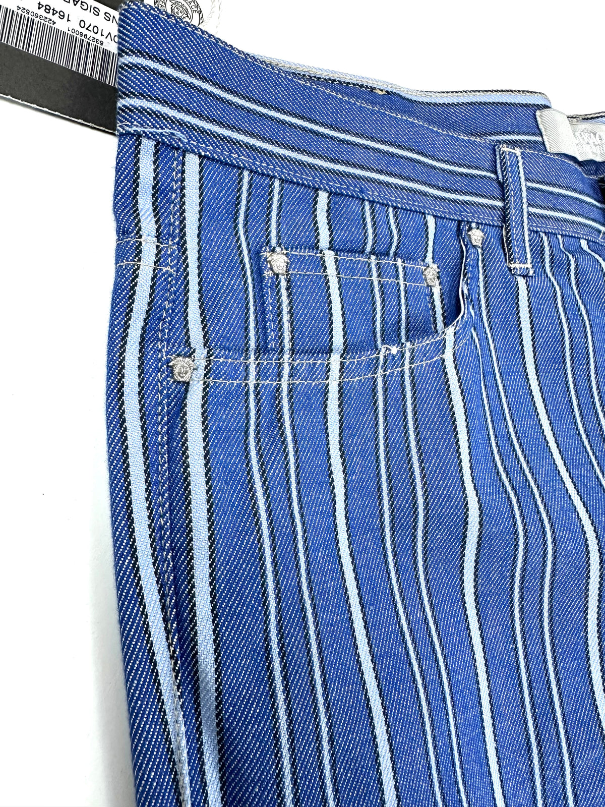 Dettaglio delle tasche anteriori del jeans con cuciture a contrasto sul denim a righe