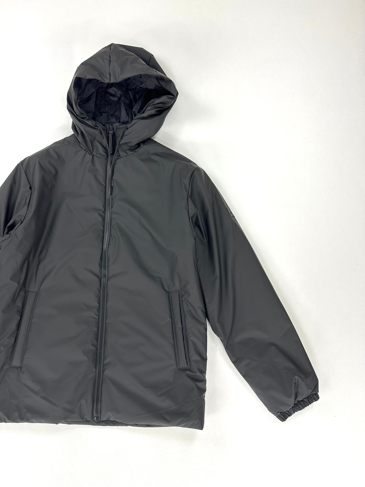 Giacca Rains nera con zip frontale coperta da patta e tasche laterali a filo