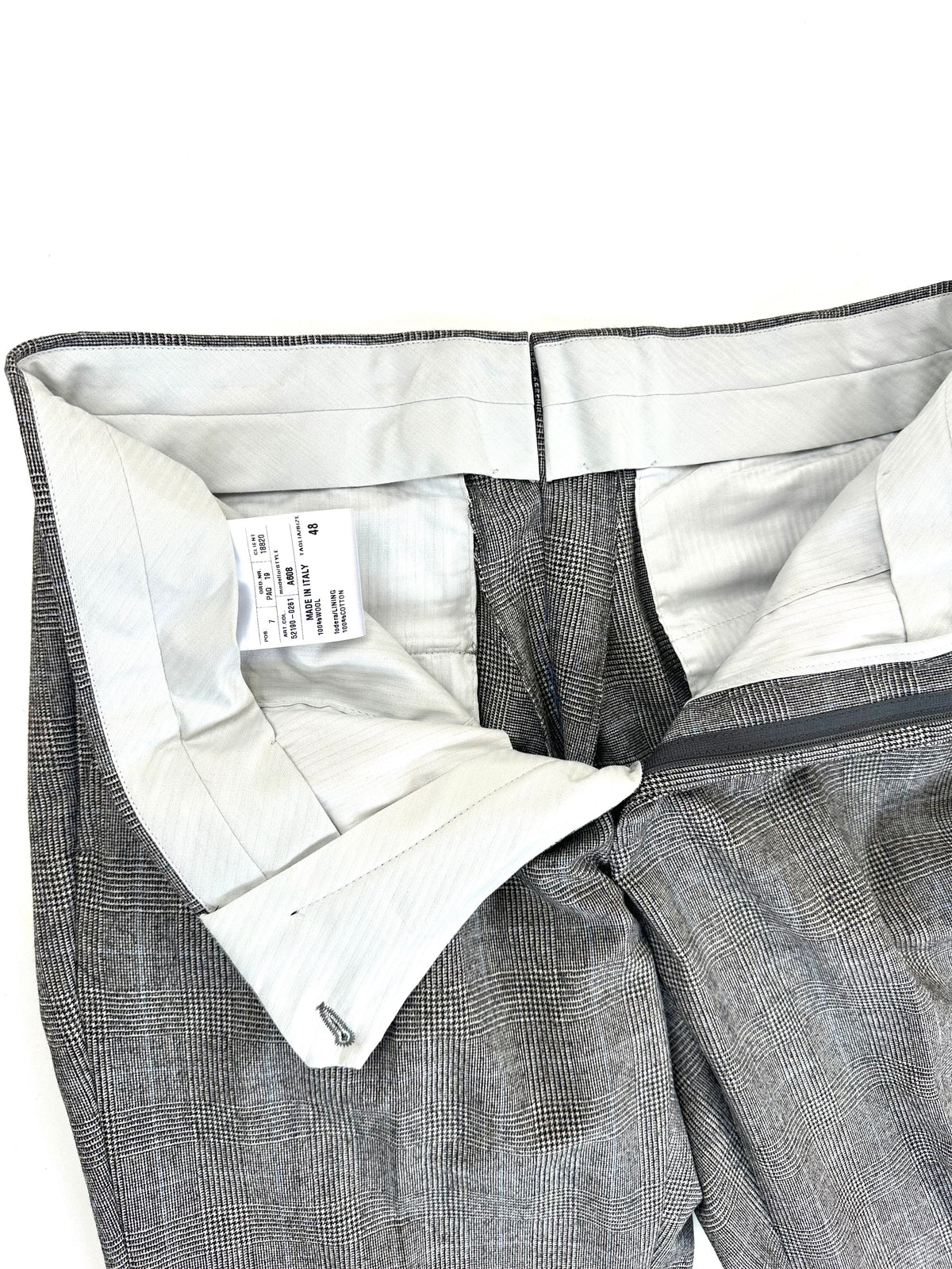 Interno della cintura del pantalone, con fodera chiara ed etichetta di taglia