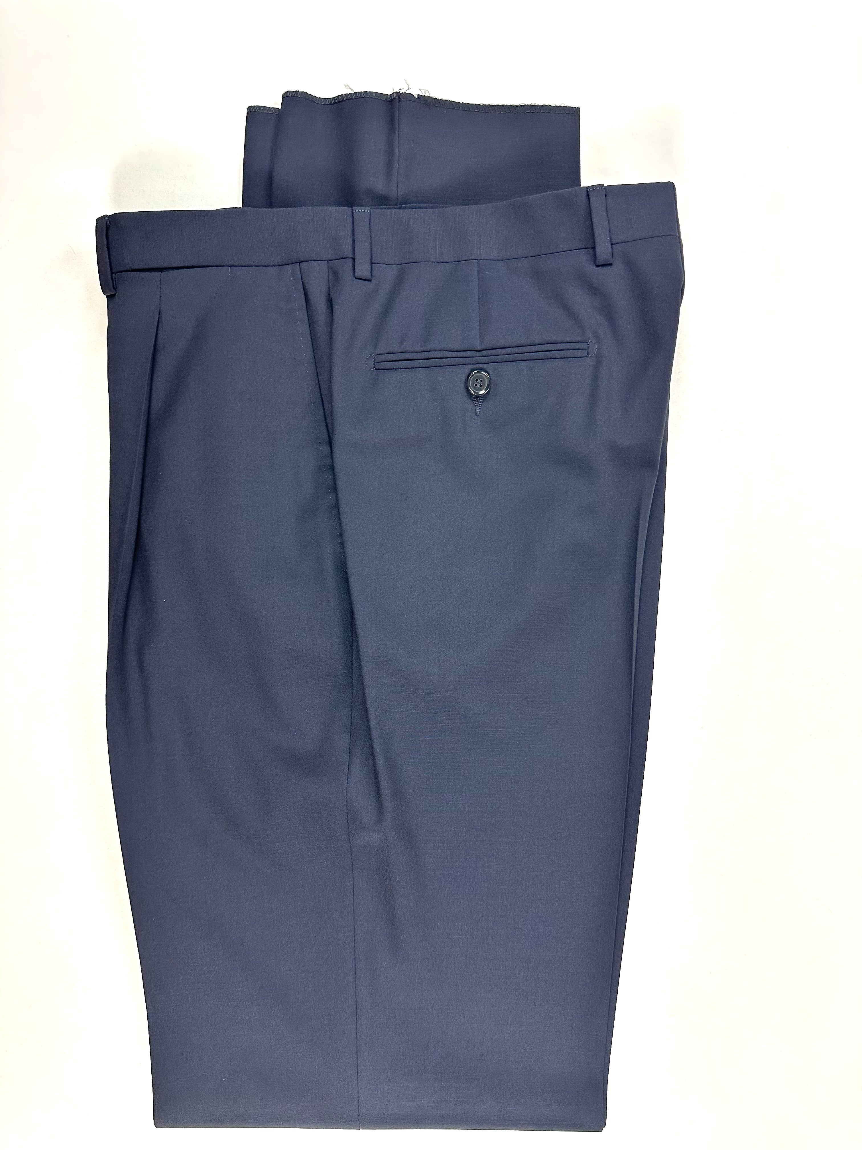 Dettaglio del pantalone piegato: vita, passanti e tasca posteriore a filetto con bottone