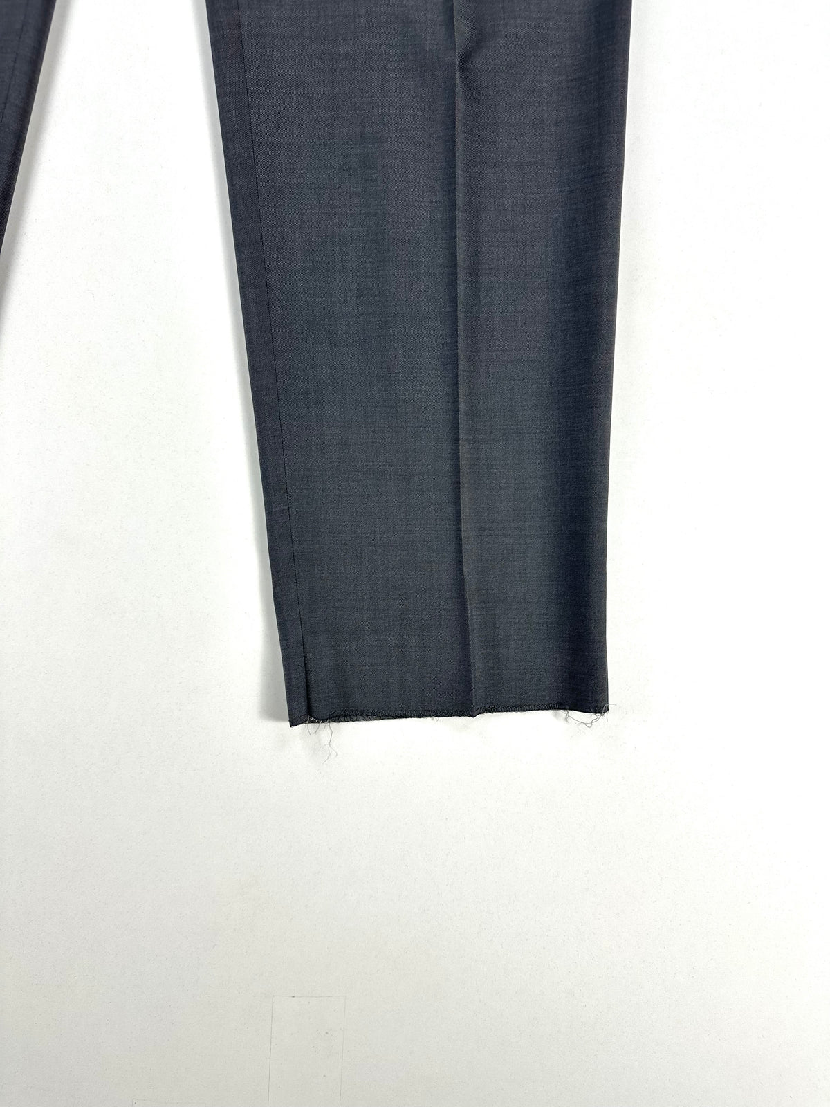 Dettaglio del fondo del pantalone lasciato grezzo, non orlato