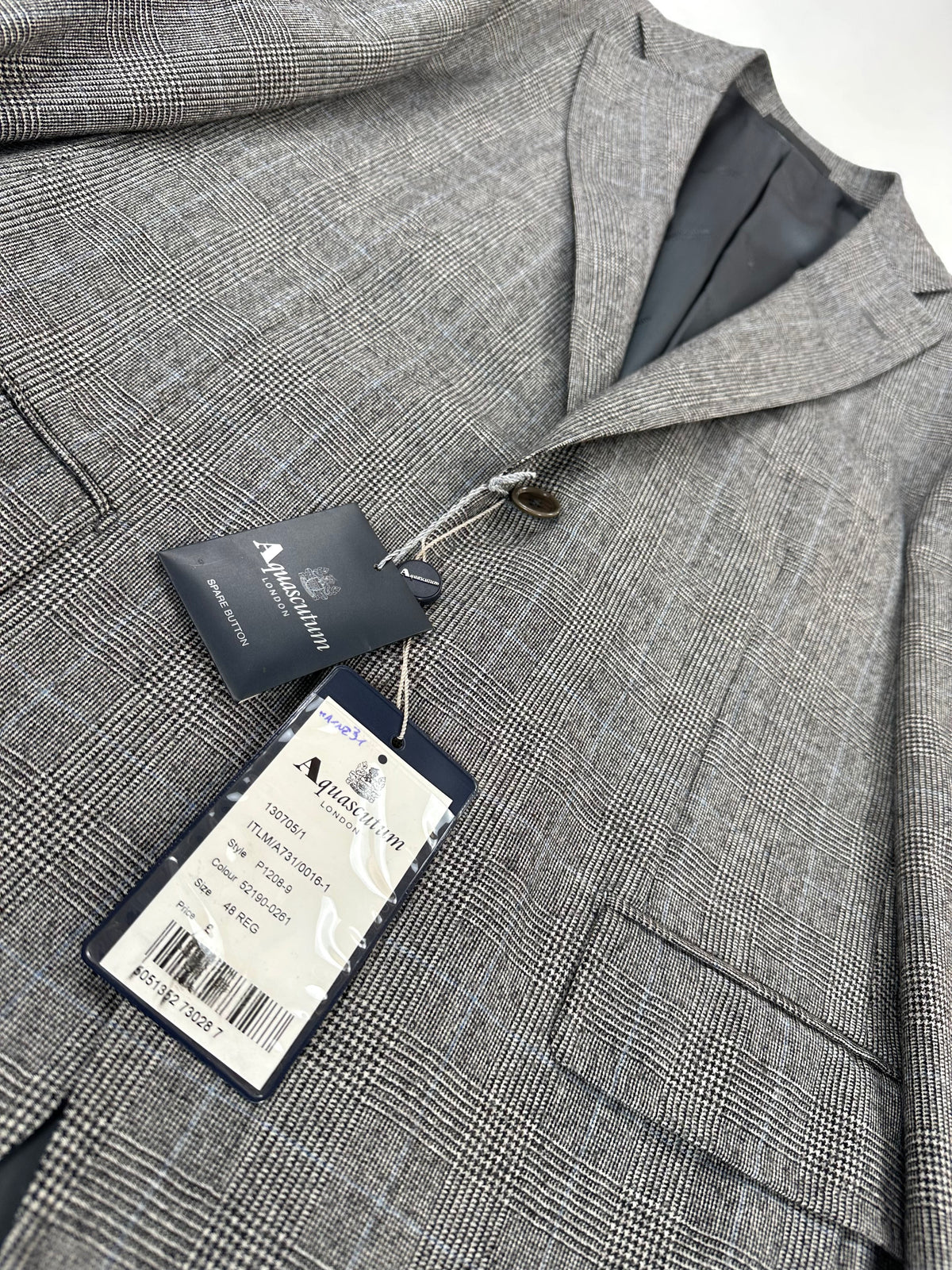 Revers della giacca sollevato, con i cartellini Aquascutum appesi all'occhiello