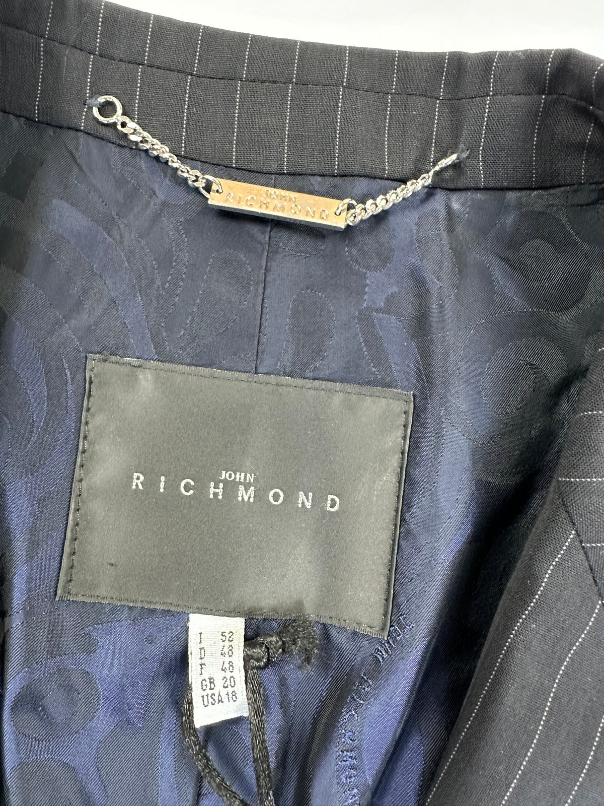 Interno della giacca con etichetta John Richmond applicata sulla fodera e appendino a catenella