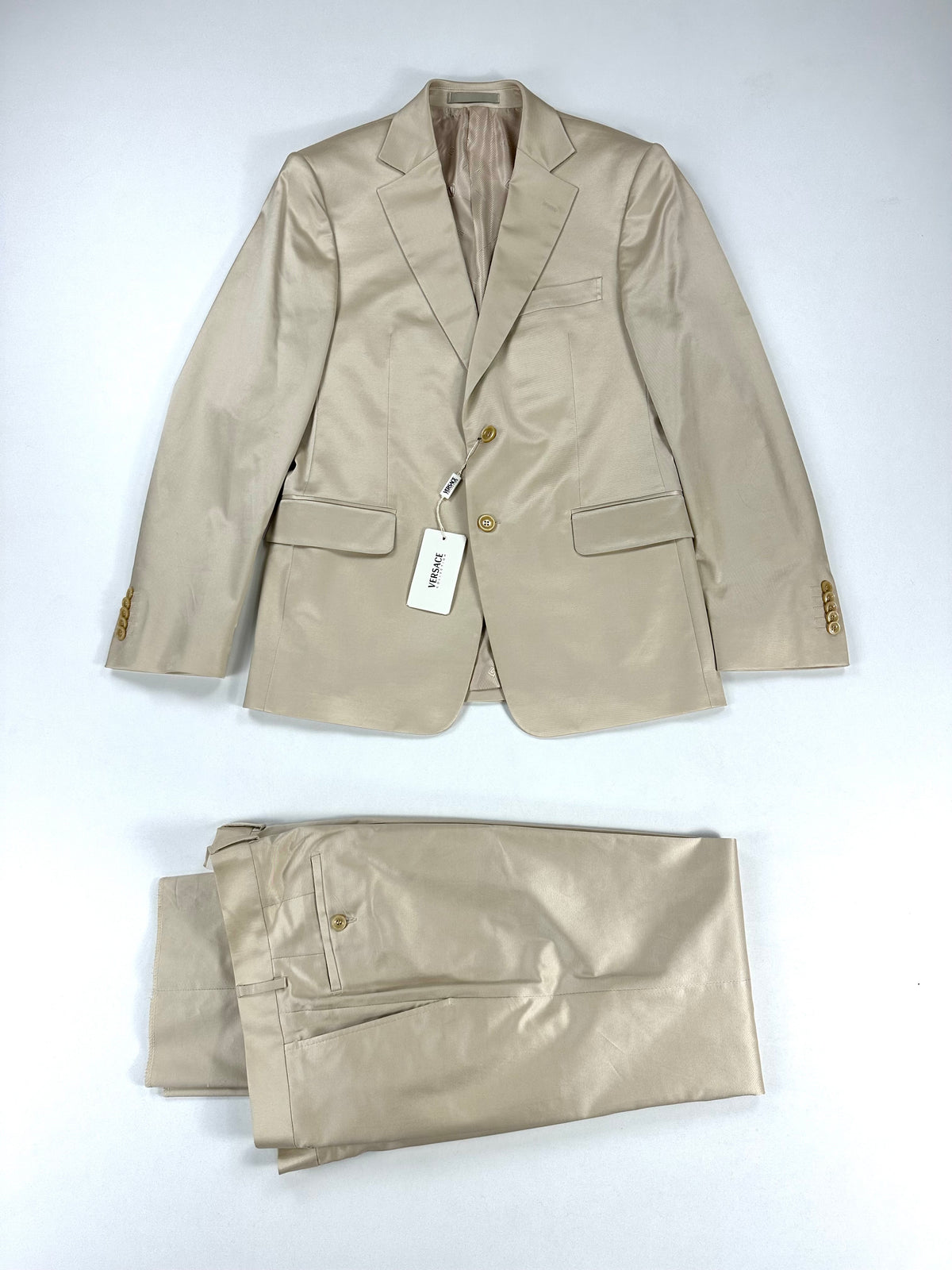 Abito Versace Collection panna in cotone e viscosa stretch, giacca a due bottoni e pantalone coordinato distesi su fondo bianco
