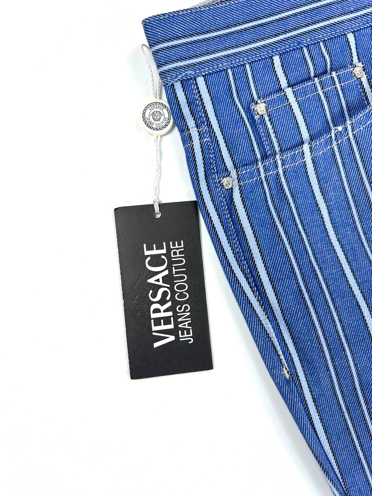 Cartellino Versace Jeans Couture appeso al jeans, con il bottone Medusa in primo piano