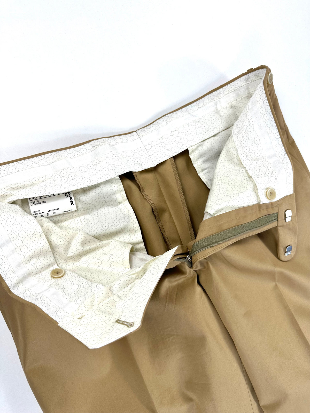 Interno del pantalone aperto: chiusura, fodera chiara e finiture in vita