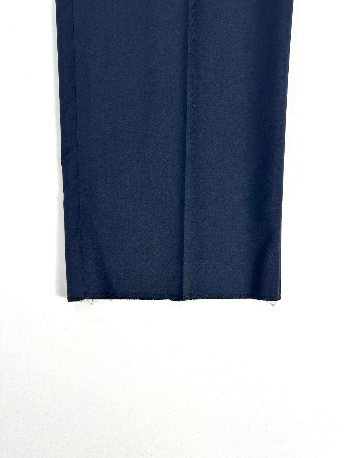 Dettaglio di una gamba del pantalone blu ripiegata, con il fondo grezzo non orlato