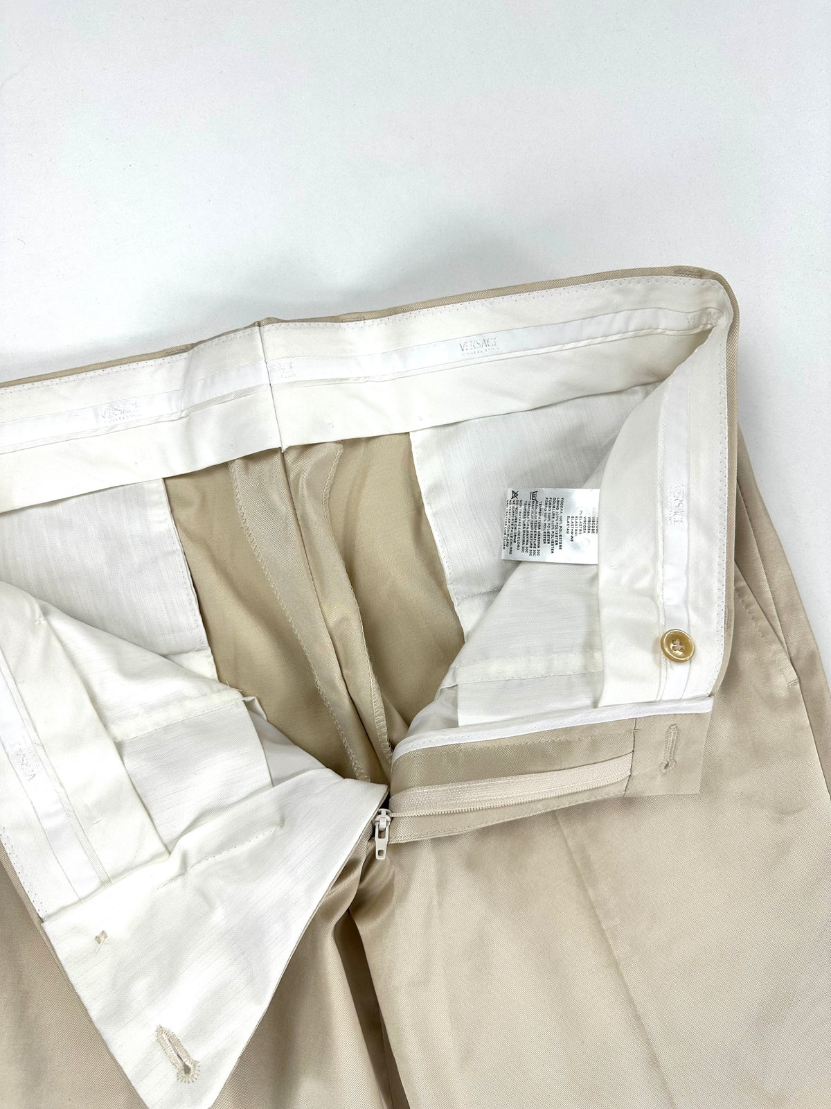 Interno del pantalone aperto: fascia in vita firmata Versace Collection, zip ed etichetta