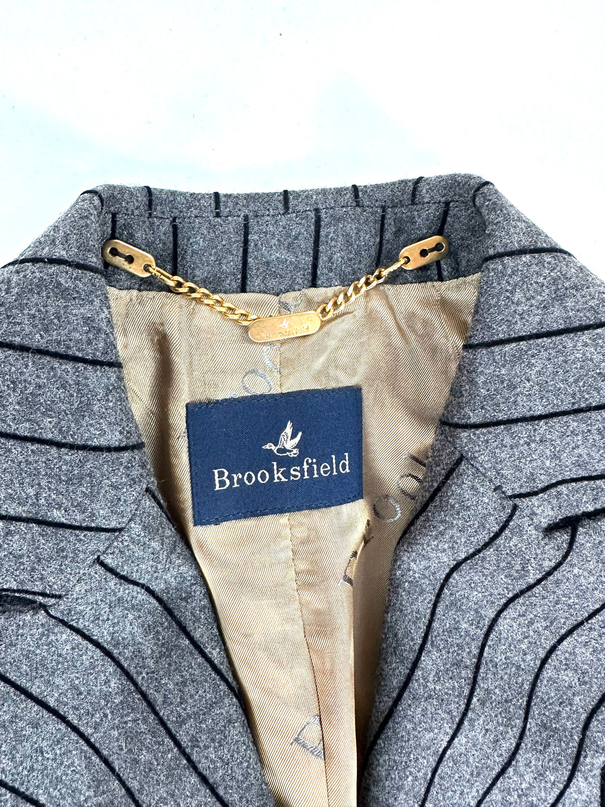 Interno della giacca Brooksfield: fodera in raso oro con catenella appendiabito ed etichetta del marchio